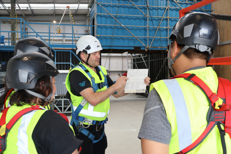 TGA photoshoot - A trainer teaching learners who are all wearing harnesses
